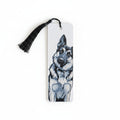A white rectangular bookmark with a black tassel, featuring a black and white painted illustration of a dog on the front, shown against a light beige background.