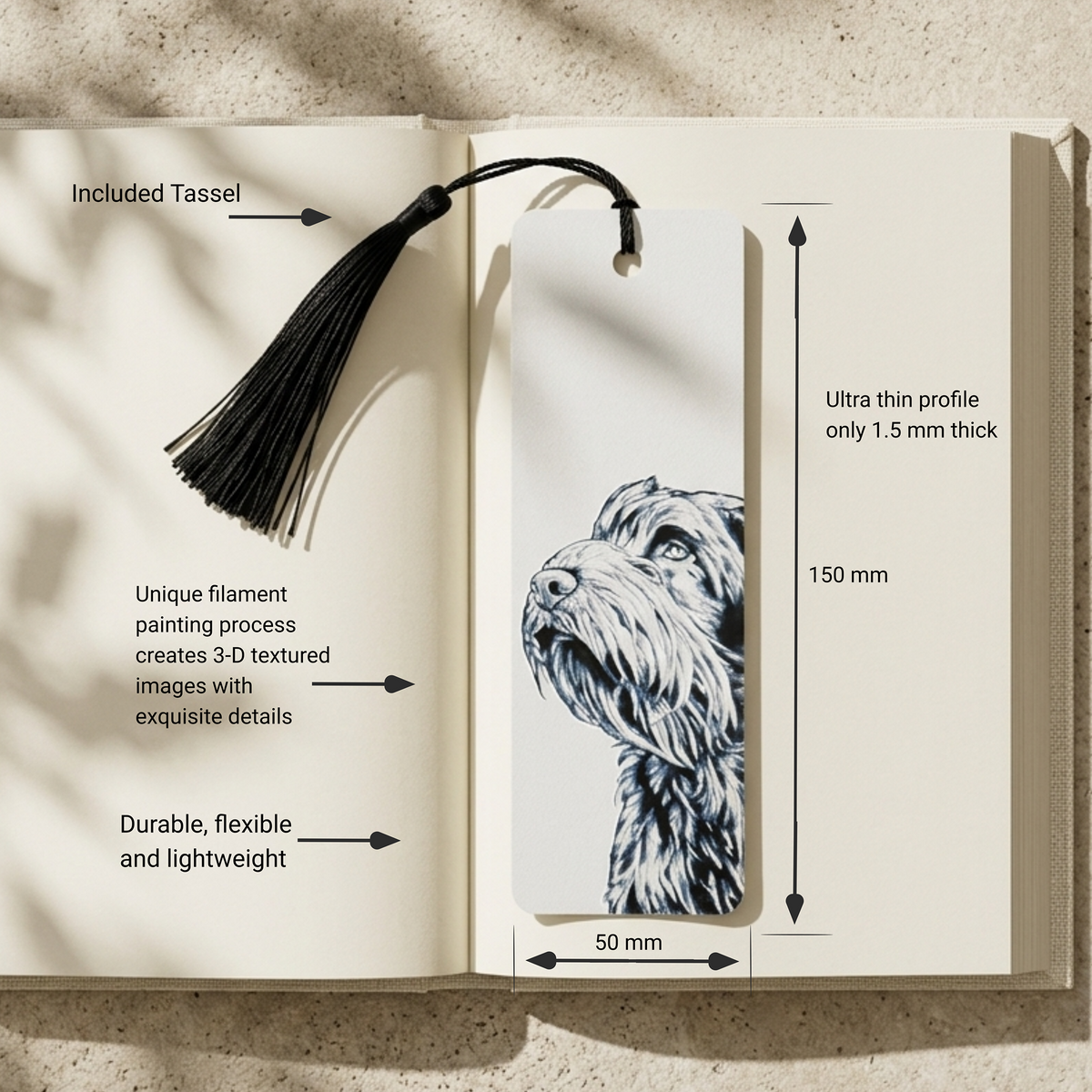 An open book displaying a bookmark with a black tassel and a detailed sketch of a dog. The image includes dimension labels showing the bookmark is 150 mm tall and 50 mm wide, with text highlighting its thin profile, durability, and included tassel.