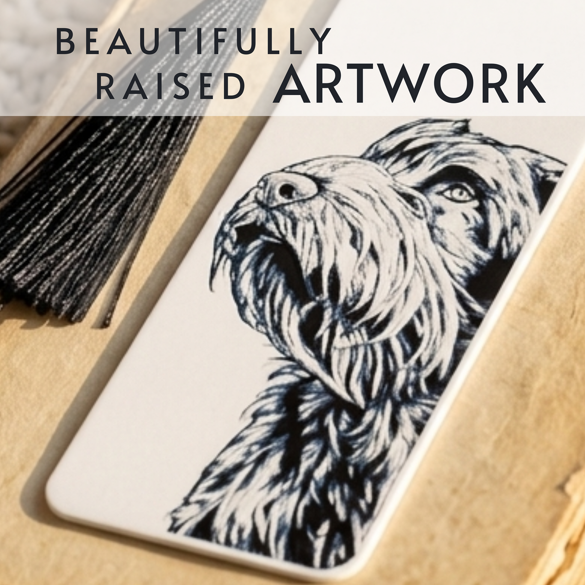 A rectangular white Bookmark featuring a black-and-white sketch of a dog, styled on a tan surface with a black tassel and overlaid text reading 'BEAUTIFULLY RAISED ARTWORK'.