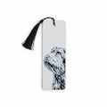 A white rectangular 3D printed bookmark with a black tassel at the top and a black-and-white illustration of a handsome scruffy dog on the right side, photographed against a light beige textured background.